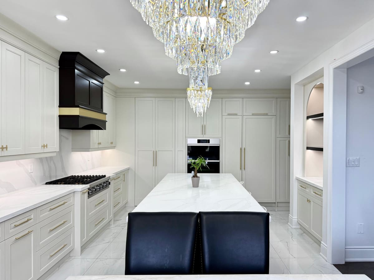 Kitchen with a black hood, full-height panelled pantry wall and a crystal chandelier over the island