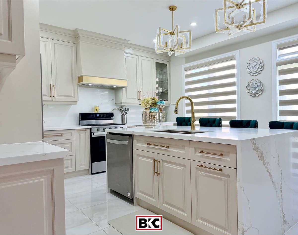 Cream raised-panel kitchen island with brass pulls and a waterfall quartz top