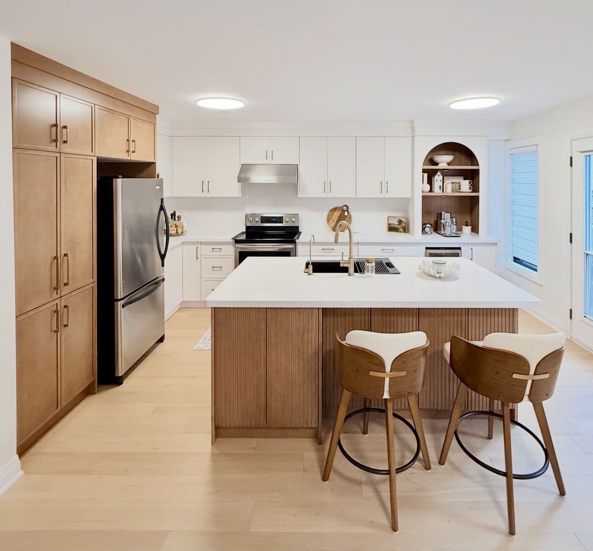 White kitchen with a fluted oak island, oak pantry wall and an arched open niche