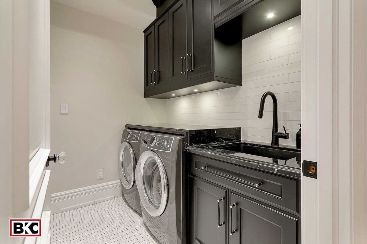 Black shaker laundry room with marble counter and under-cabinet lighting