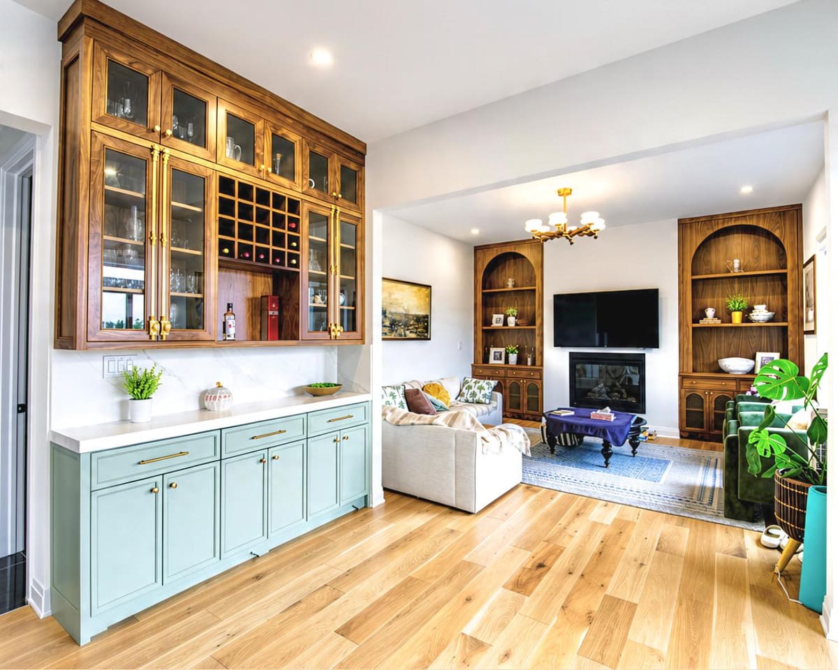 Walnut glass-front bar cabinets over a soft teal buffet, with arched walnut built-ins beyond