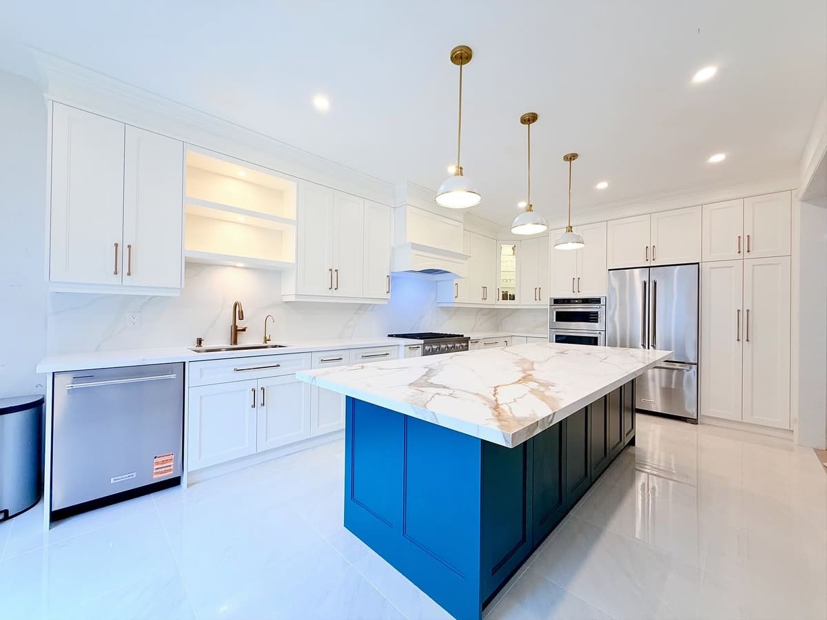 White shaker kitchen with a blue island and brass pendant lights