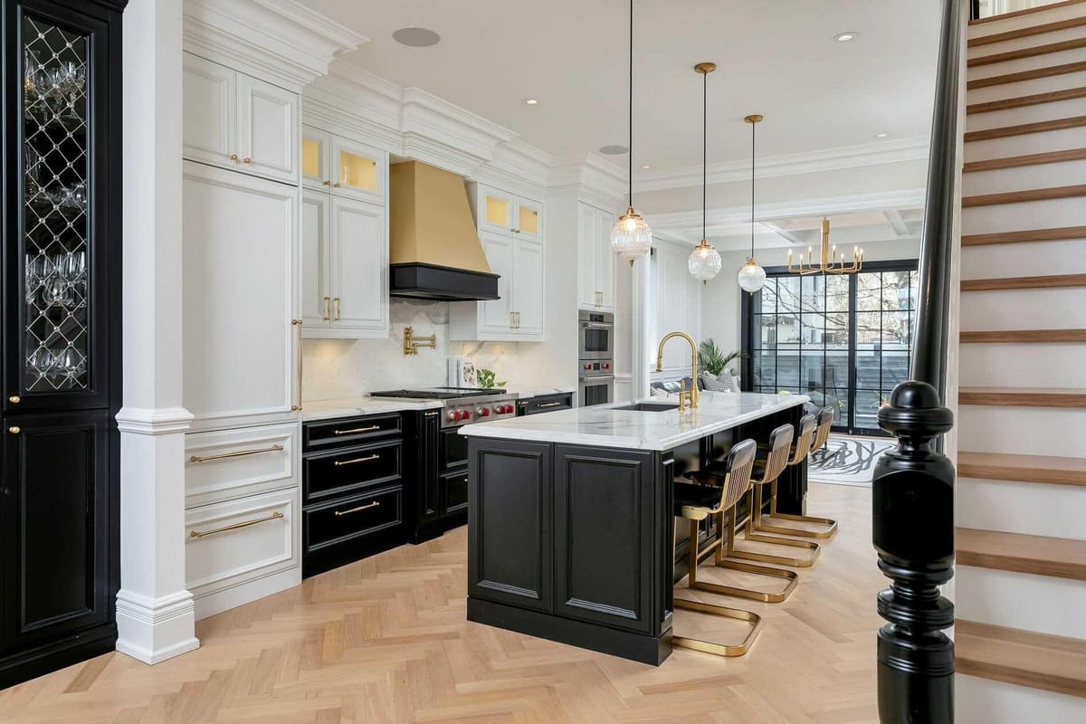 Luxury white kitchen with a black island, brass hood and herringbone floor