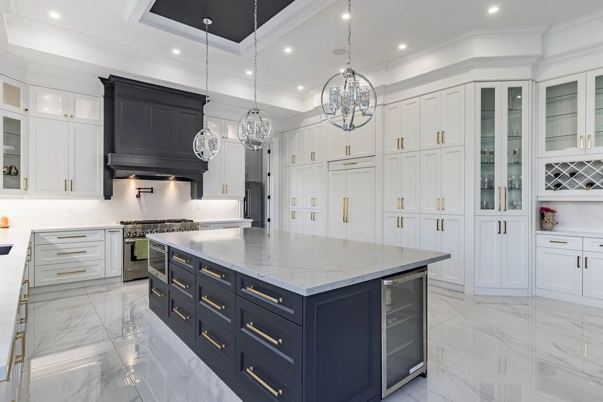 White kitchen with a navy island, coffered ceiling and marble floor