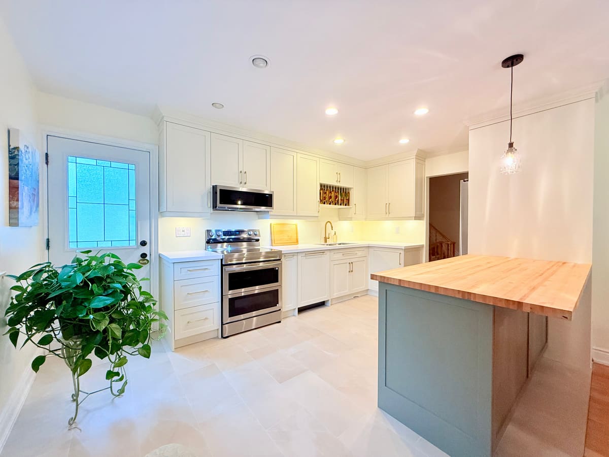 White shaker kitchen with a sage green island and butcher-block top