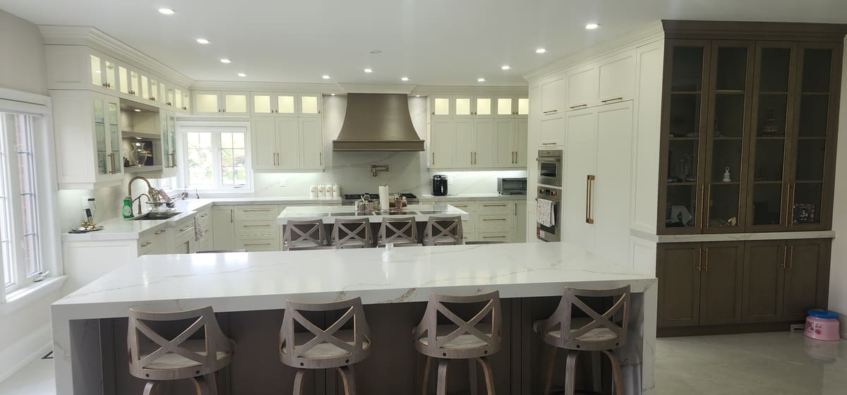 White kitchen with a waterfall quartz island and a walnut glass hutch