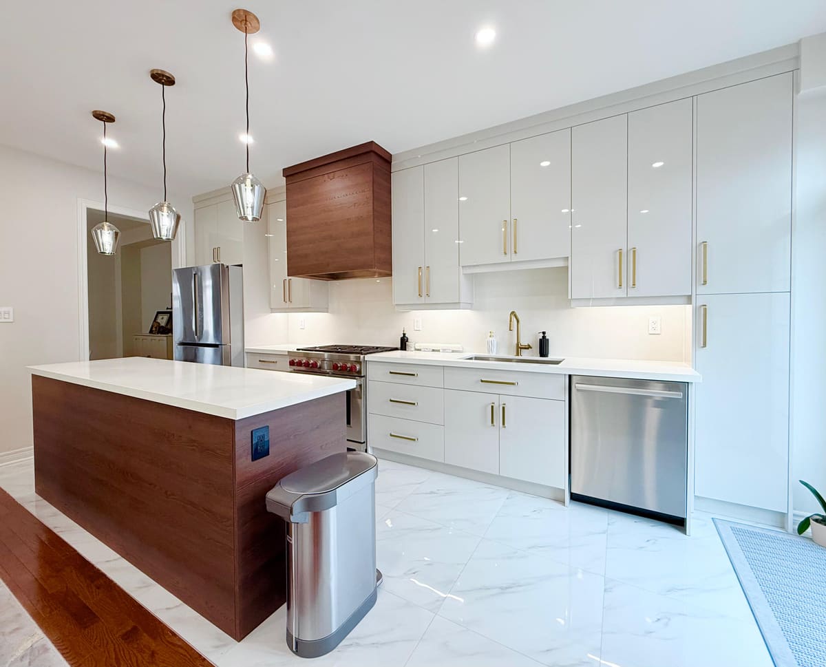 White flat-panel kitchen with a walnut-wrapped island and glass pendants